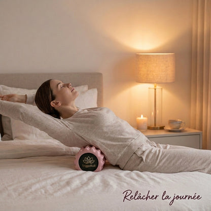 Femme allongée sur son lit qui étire son dos sur le rouleau TriggeRoll le soir